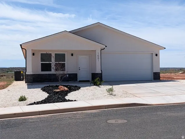 View of front of home featuring stone siding, concrete driveway, an attached garage, and stucco siding