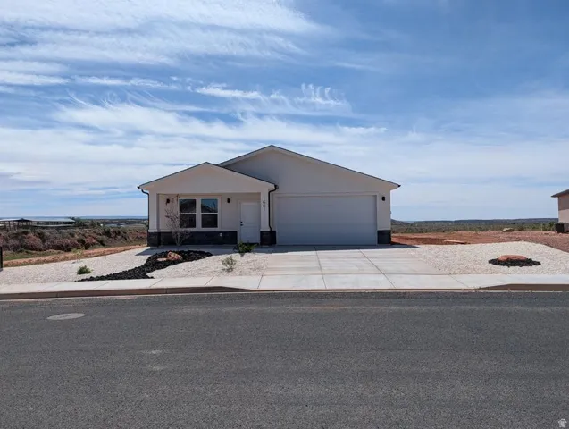 View of front of property featuring concrete driveway, an attached garage, and stucco siding