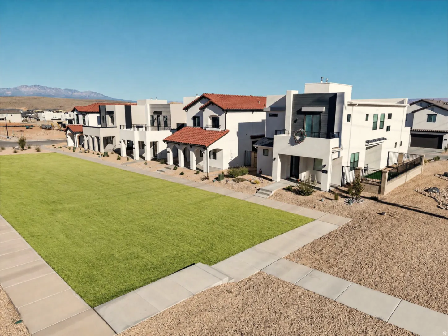 Modern architectural design featuring white stucco exteriors and flat roofs, complemented by red tile accents on select buildings