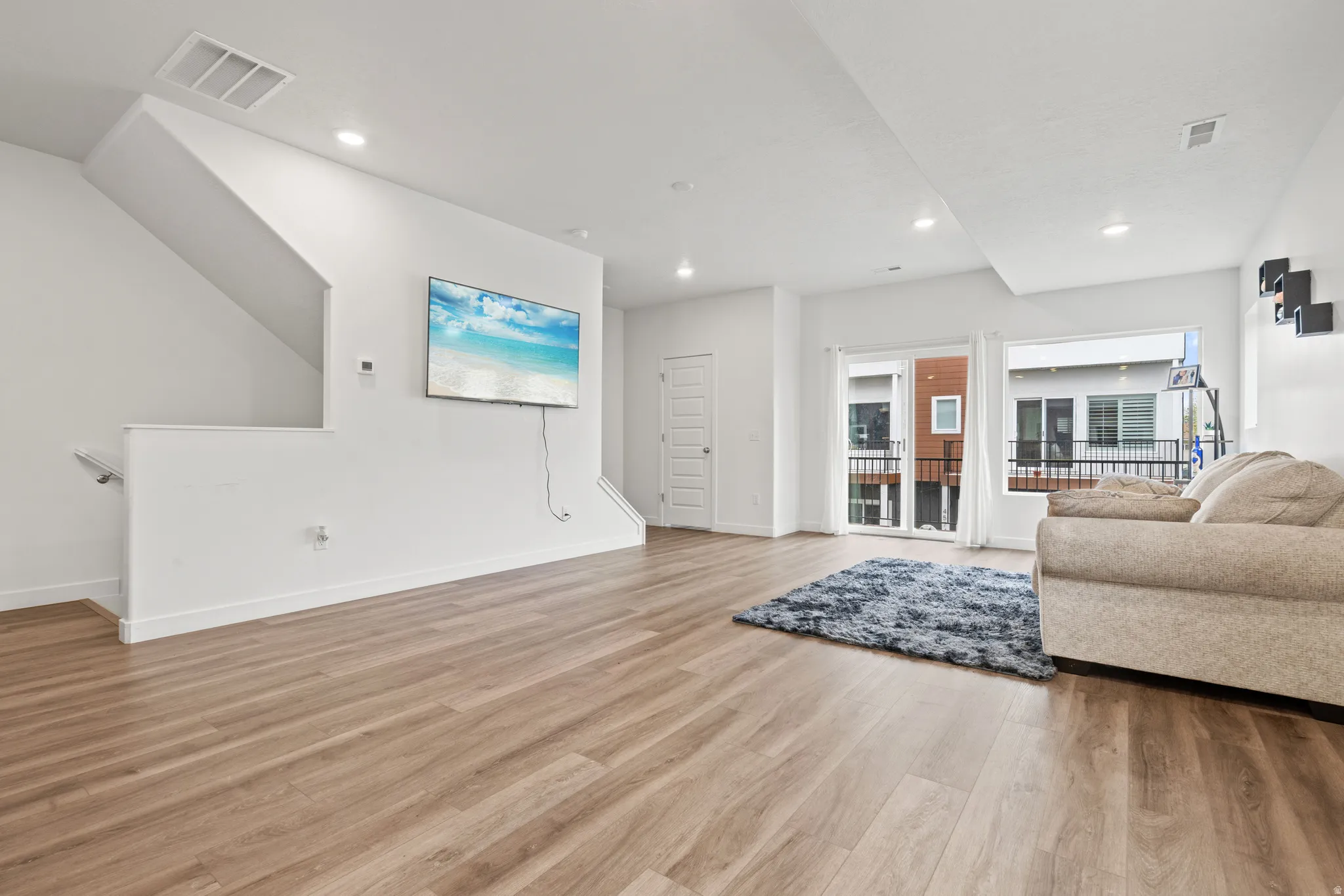 Living area with light wood-style floors and recessed lighting