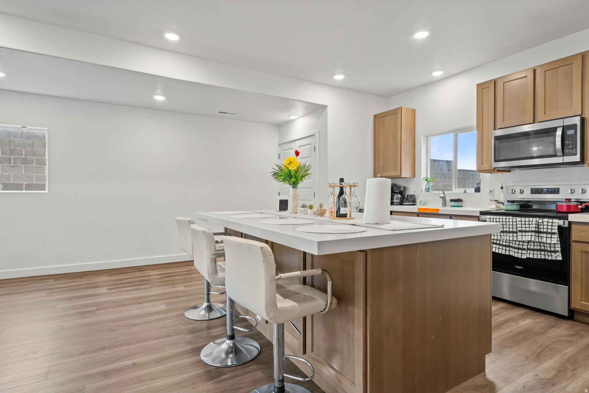 Kitchen with stainless steel appliances, a kitchen island, a kitchen bar, light wood-type flooring, and recessed lighting