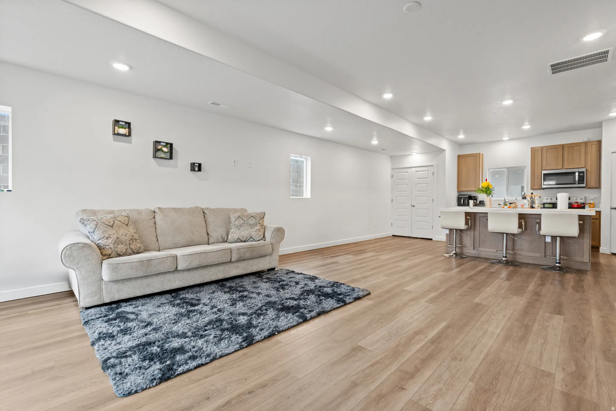 Living area with light wood finished floors and recessed lighting