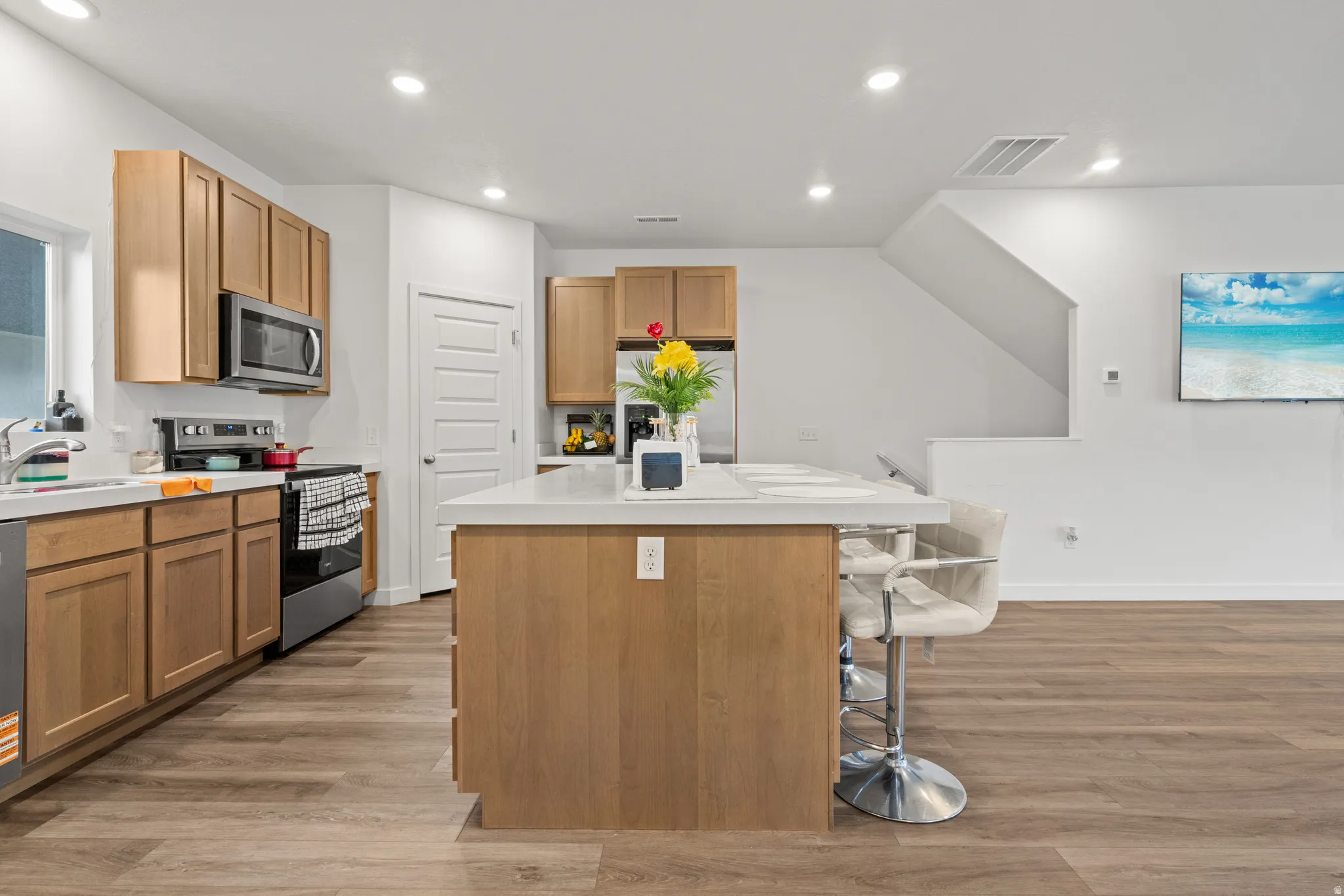 Kitchen with a center island, stainless steel appliances, light countertops, light wood-style floors, and recessed lighting