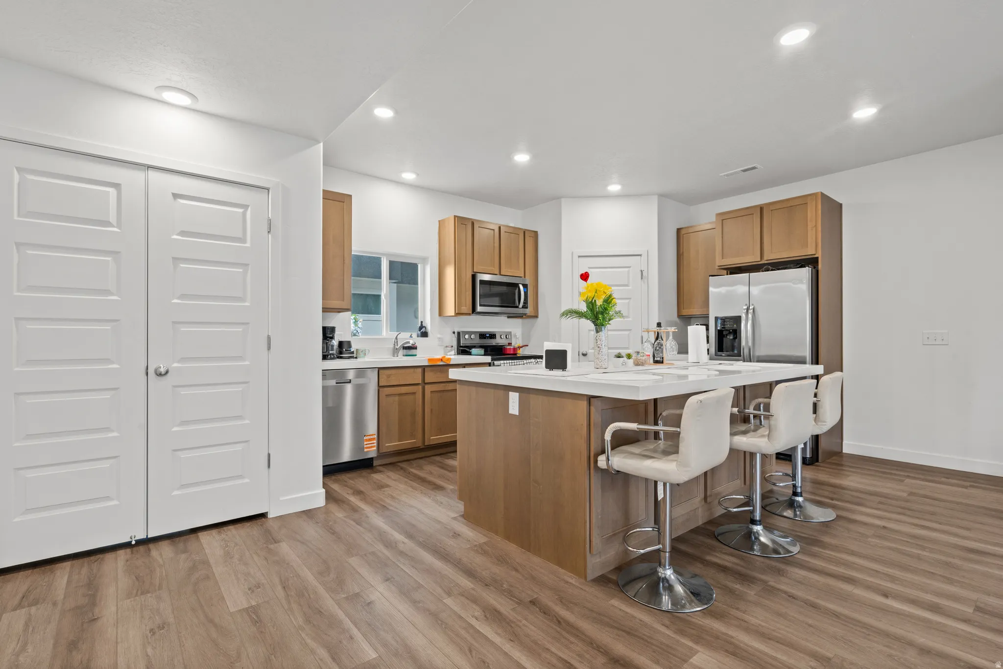 Kitchen featuring a breakfast bar area, light countertops, a kitchen island, wood finish cabinetry, and recessed lighting