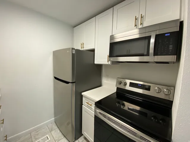 Kitchen featuring stainless steel appliances, white cabinetry, and light countertops