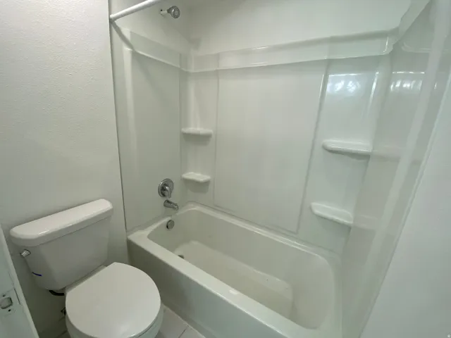 Bathroom with a textured wall and bathing tub / shower combination