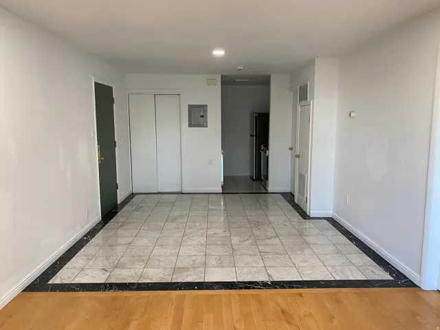 Unfurnished bedroom with inlaid floor details, freestanding refrigerator, light wood-style flooring, electric panel, and recessed lighting