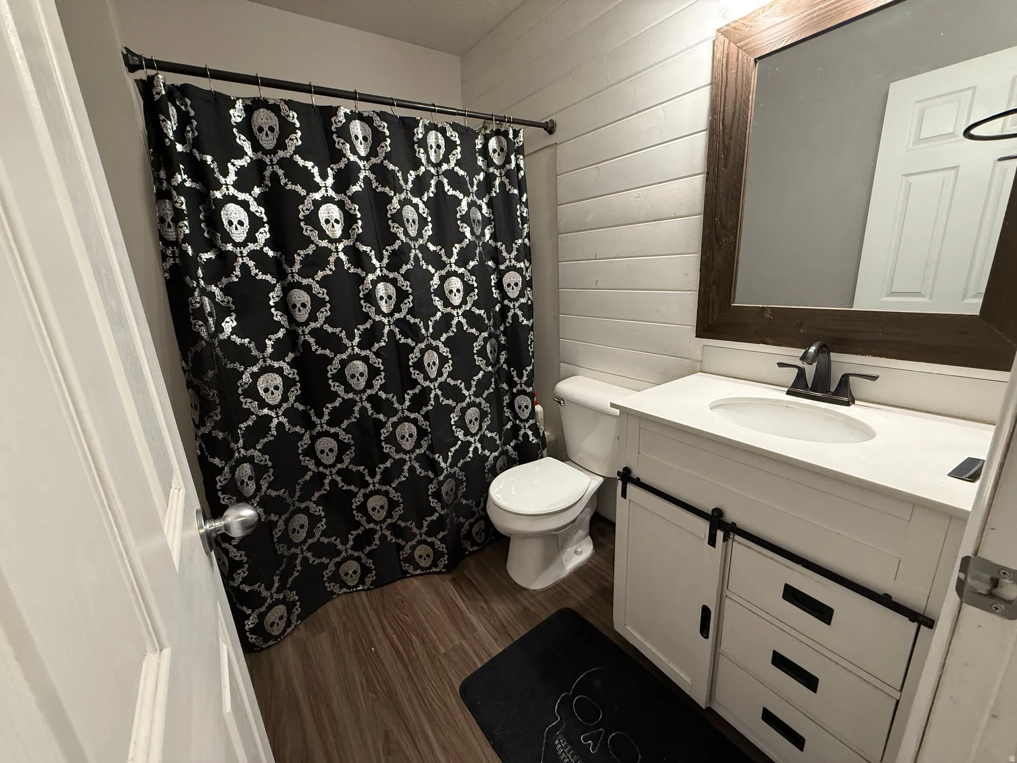 Bathroom featuring vanity, dark wood-style floors, wooden walls, and a shower with curtain
