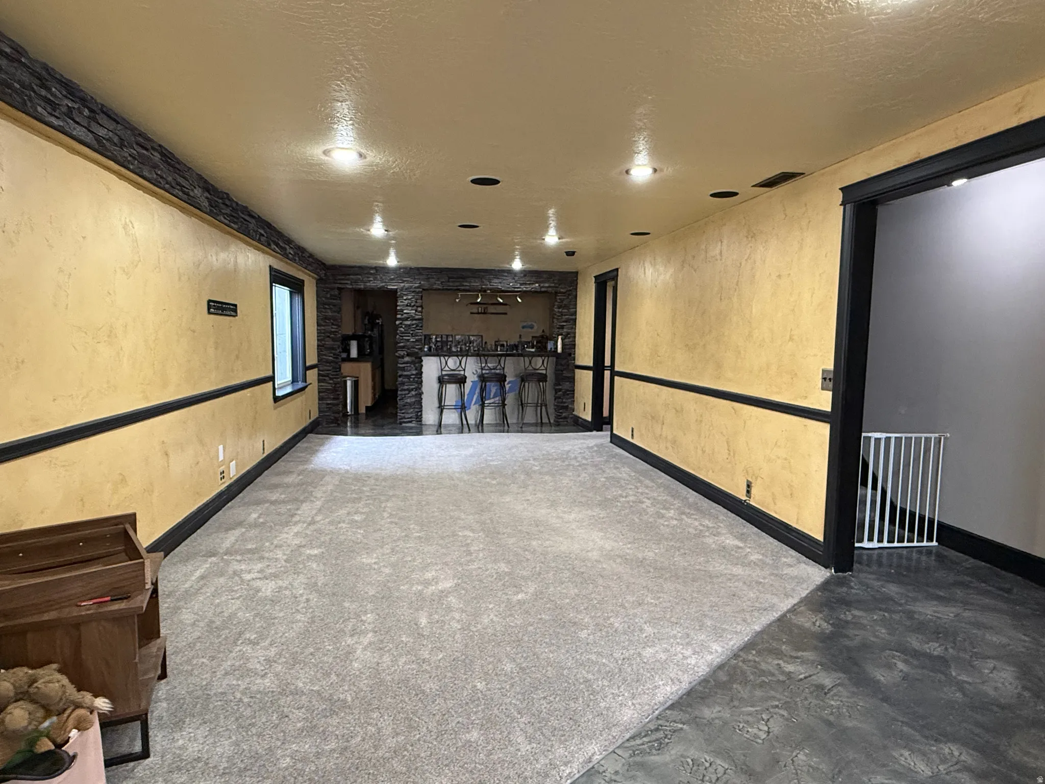 Cinema room with a textured wall, a textured ceiling, a community bar, and concrete flooring