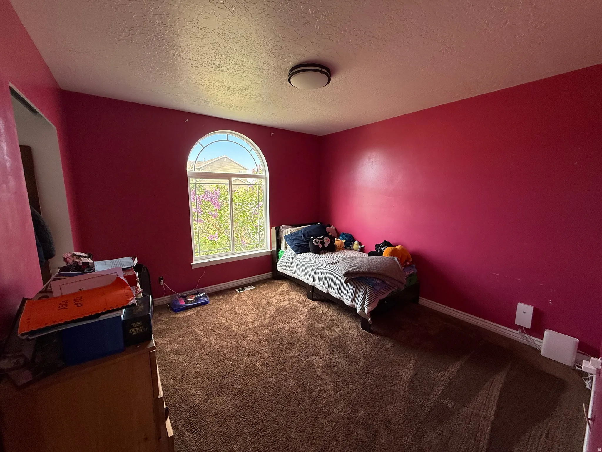 Carpeted bedroom featuring a textured ceiling and baseboards