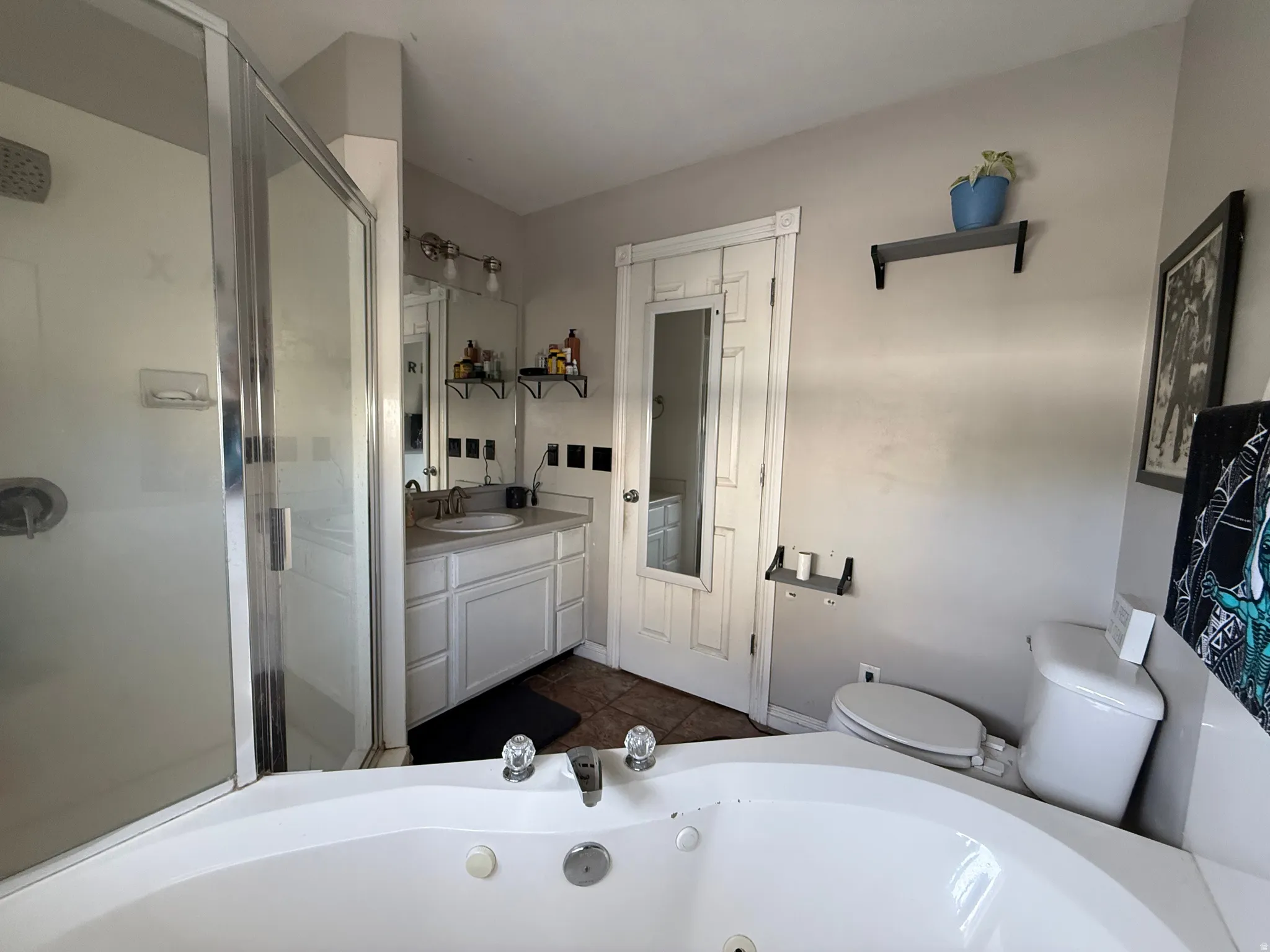 Full bath with vanity, a tub with jets, a shower stall, and dark tile patterned floors