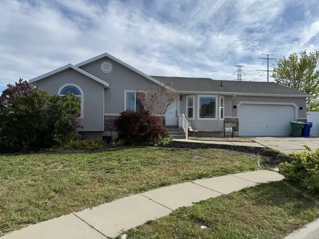 Single story home with stucco siding, a garage, a front yard, driveway, and a shingled roof