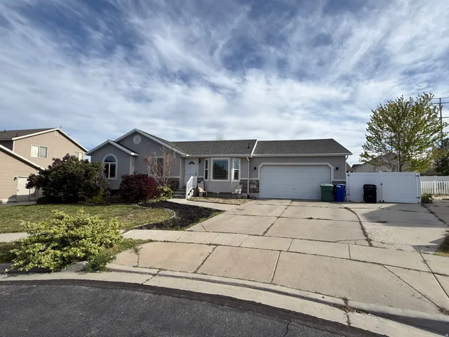 Ranch-style house featuring concrete driveway, an attached garage, stucco siding, a gate, and roof with shingles