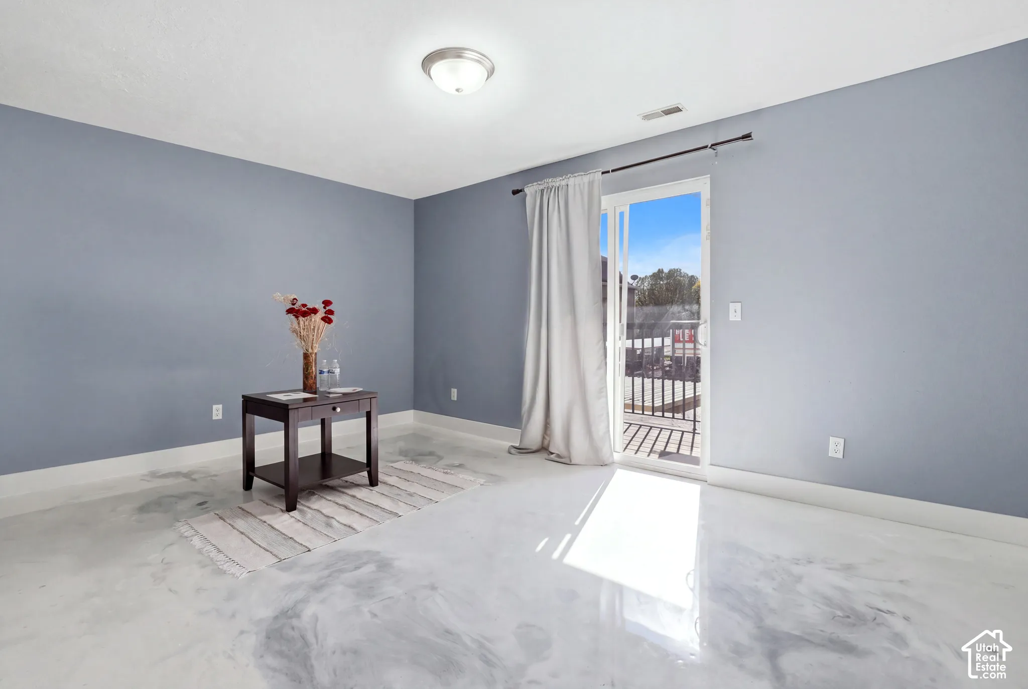 Interior space featuring high-gloss polished concrete flooring, flush-mount ceiling lighting, and a sliding glass door providing external access