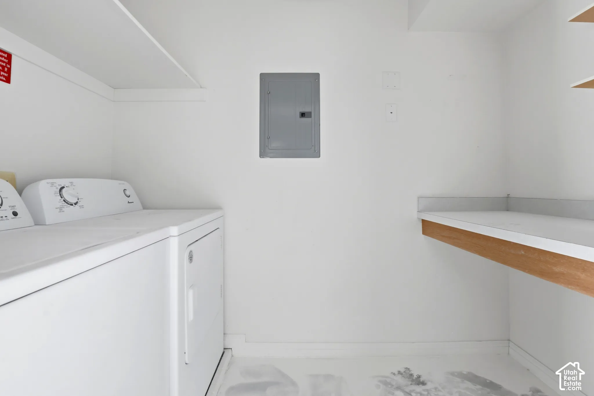 Laundry room featuring white shelving, a built-in folding counter with wood-tone edging, and an electrical service panel