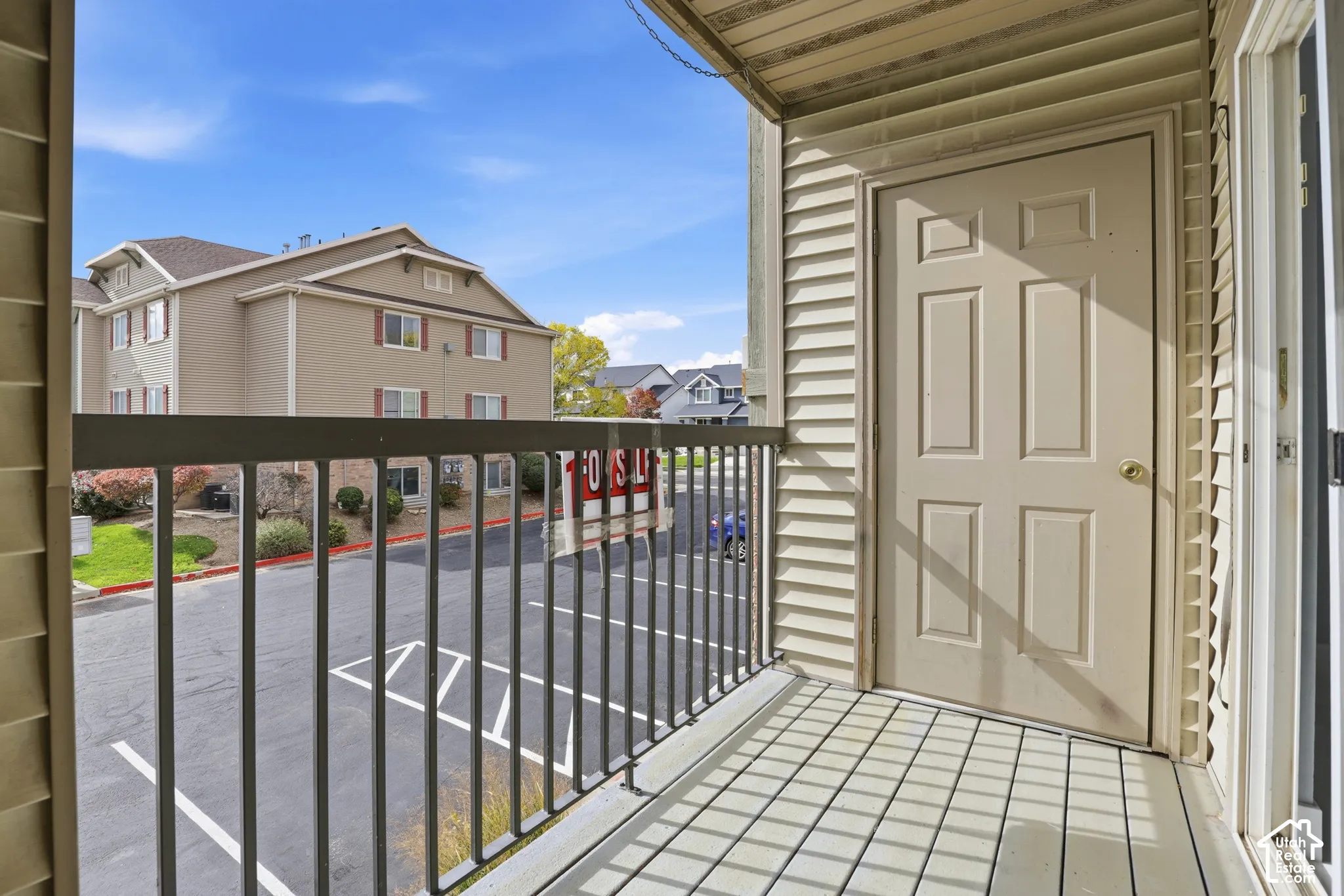 Covered exterior balcony featuring horizontal siding, a paneled door, and a metal railing