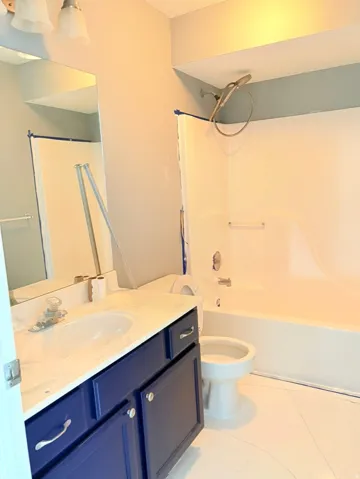 Bathroom with vanity, tub / shower combination, and light tile patterned flooring