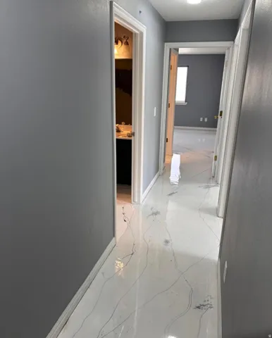 Hall featuring baseboards and light marble finish floors