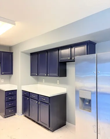 Kitchen featuring stainless steel refrigerator with ice dispenser, light countertops, and blue cabinets