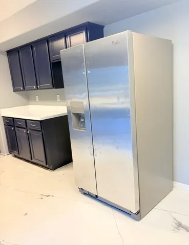 Kitchen with stainless steel fridge with ice dispenser and light countertops