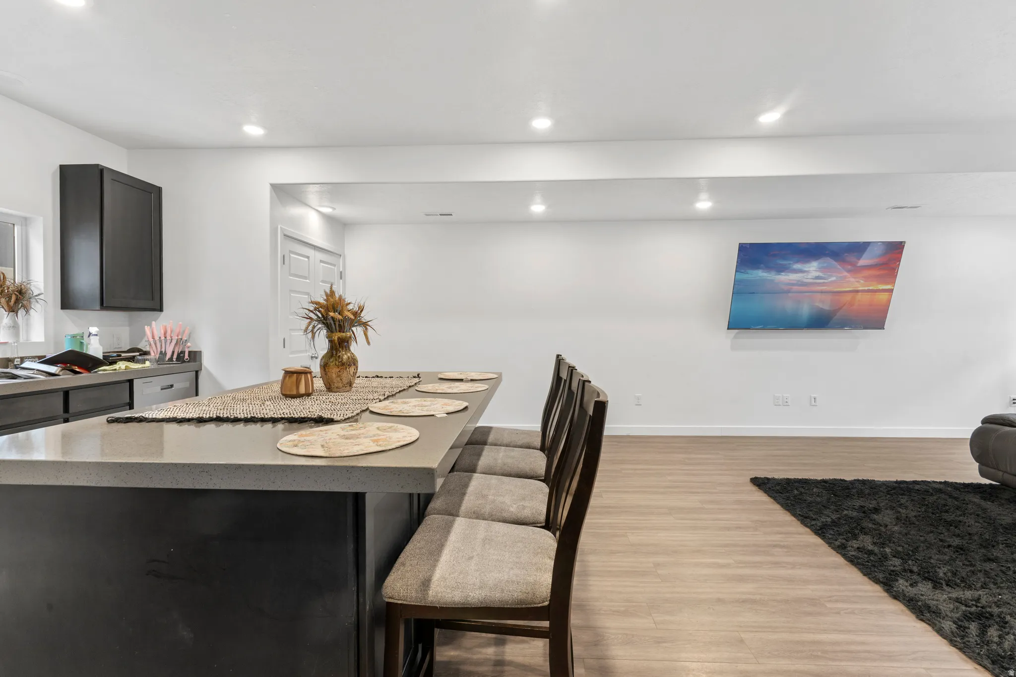 Kitchen featuring light wood finished floors, dark cabinets, a kitchen island, a breakfast bar, and recessed lighting