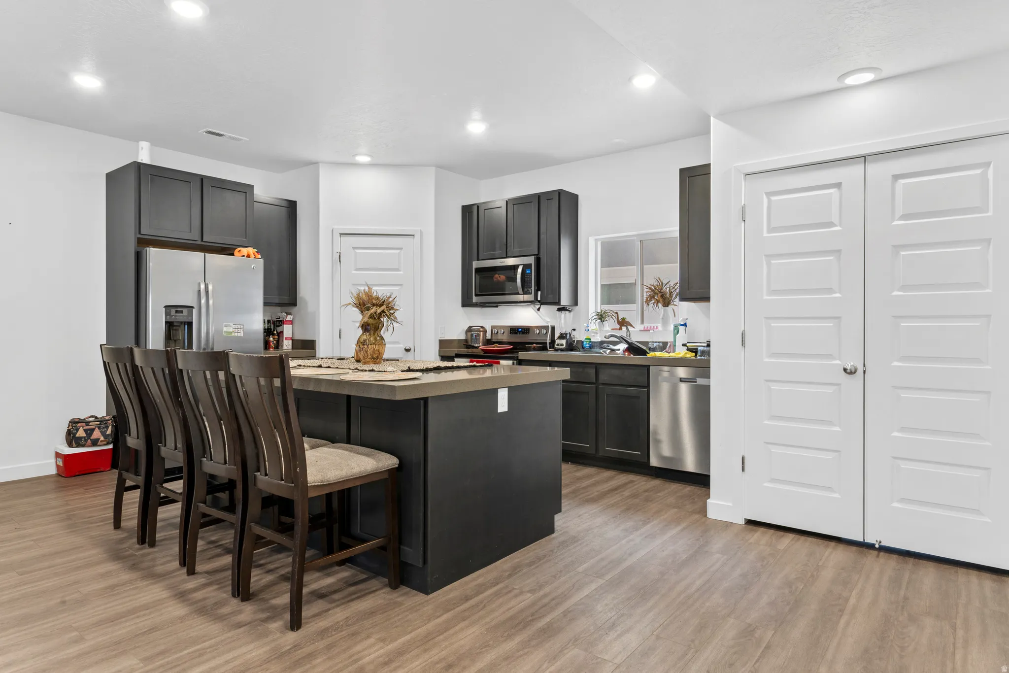 Kitchen featuring a breakfast bar area, a kitchen island, light wood-type flooring, stainless steel appliances, and recessed lighting
