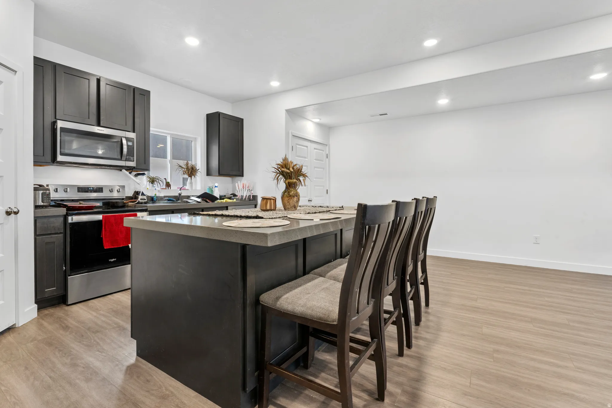 Kitchen featuring a center island, stainless steel appliances, a kitchen bar, light wood finished floors, and recessed lighting