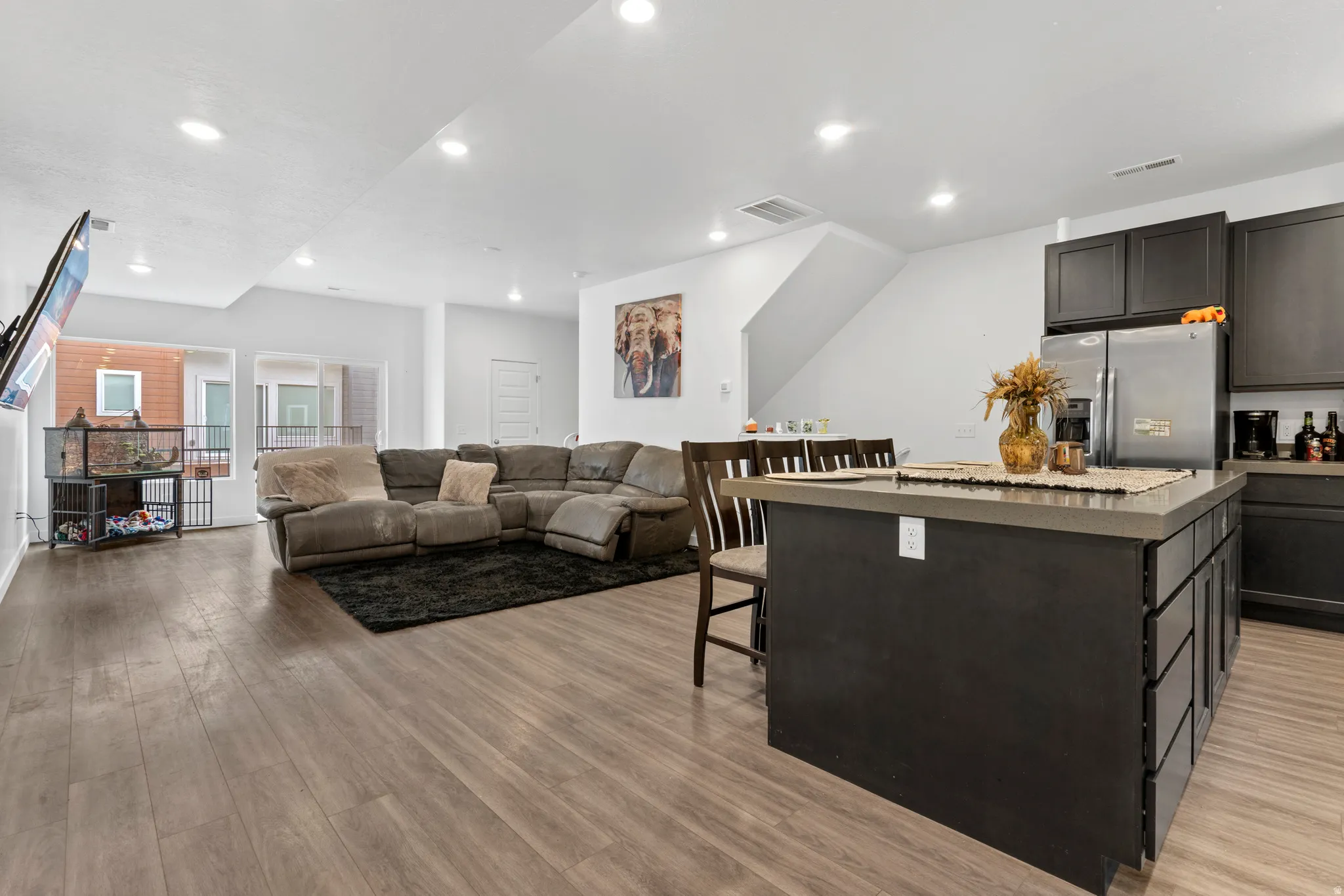 Kitchen featuring a kitchen island, a breakfast bar, stainless steel fridge, open floor plan, and recessed lighting