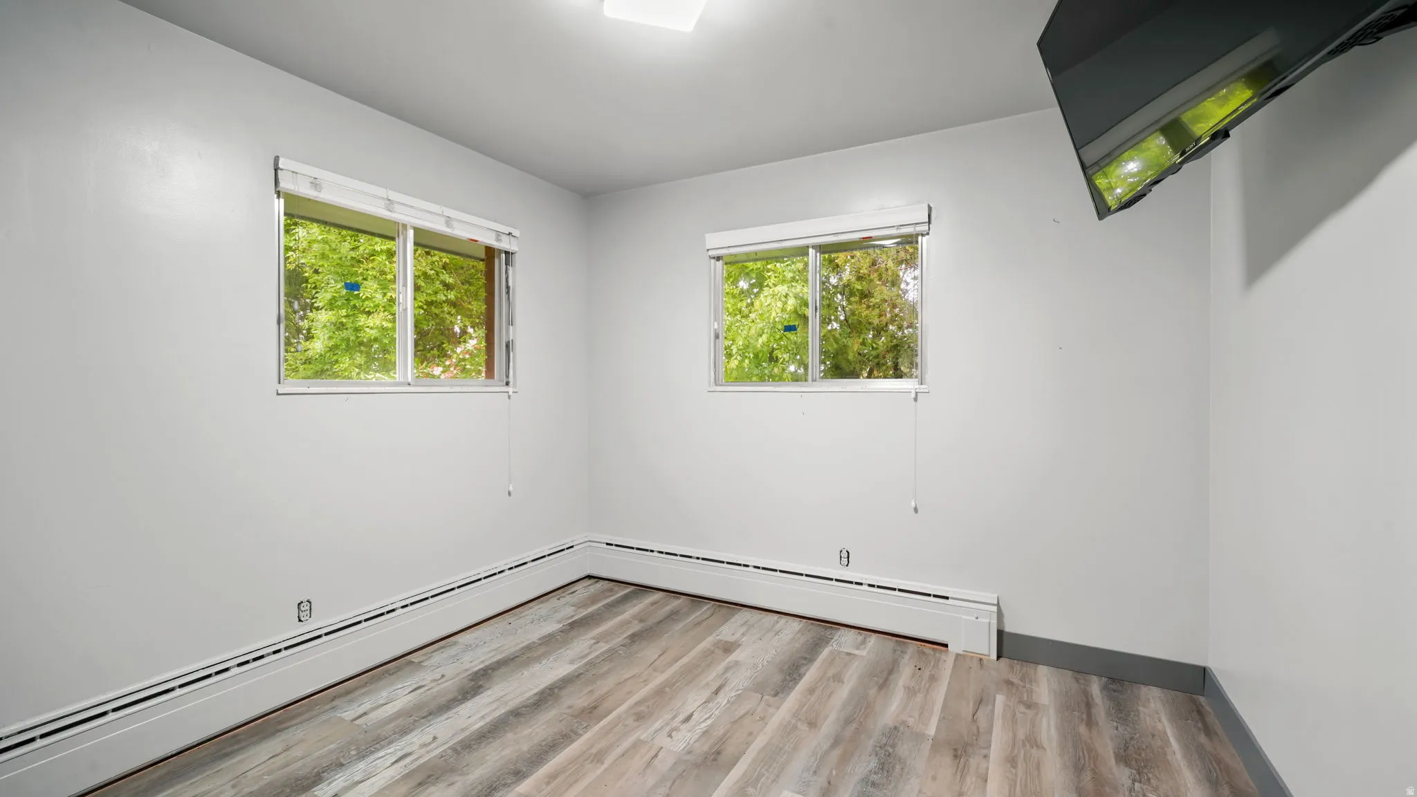 Unfurnished room with light wood-style flooring, healthy amount of natural light, and baseboard heating