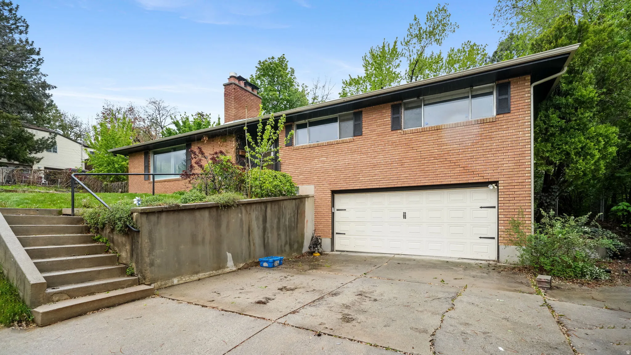 View of front of home featuring a chimney, concrete driveway, an attached garage, and brick siding