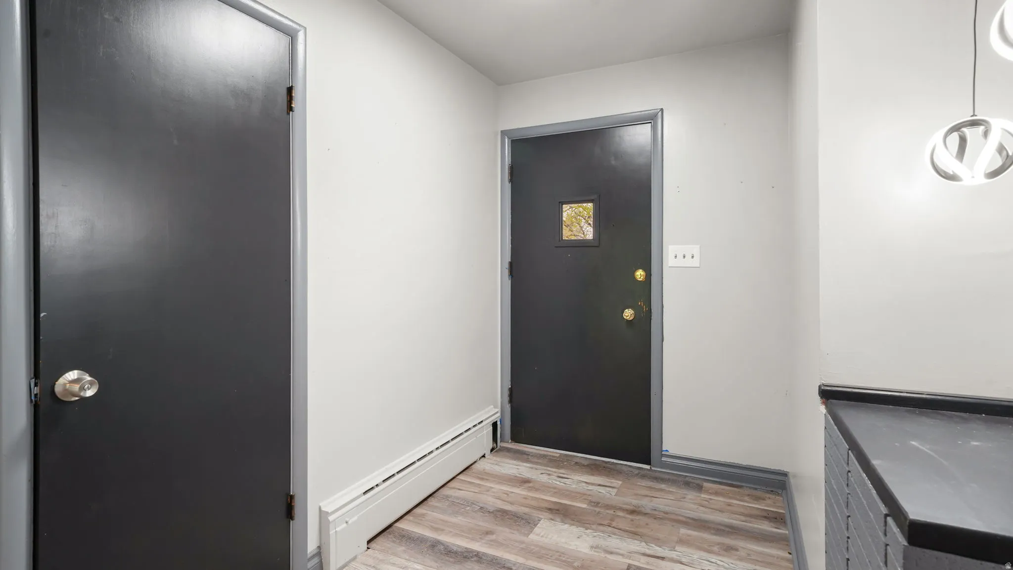 Doorway featuring baseboard heating and wood finished floors