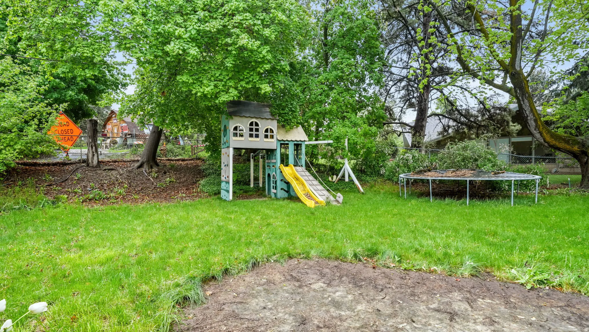 View of yard featuring a trampoline and a playground