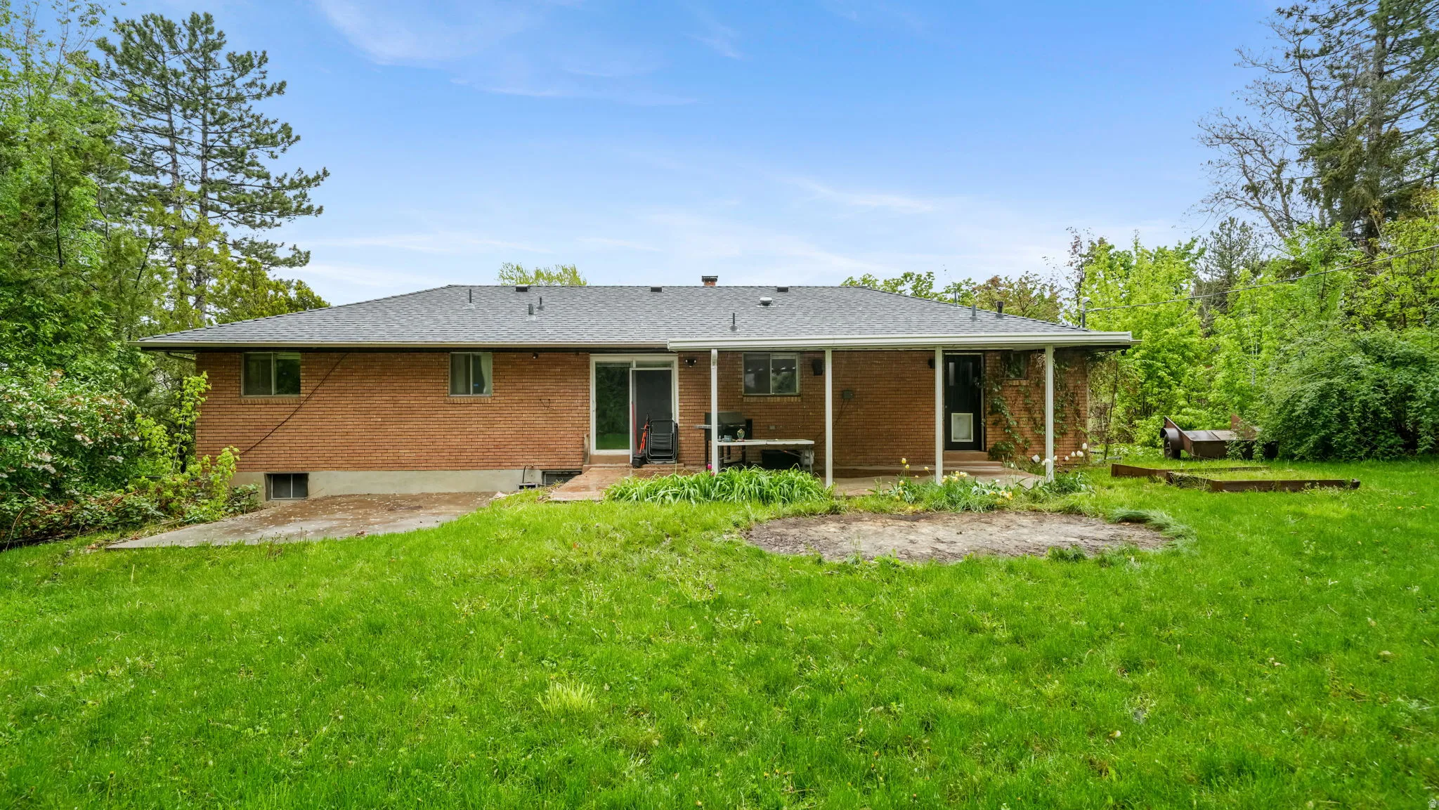 Back of property featuring a yard, a patio, brick siding, and roof with shingles