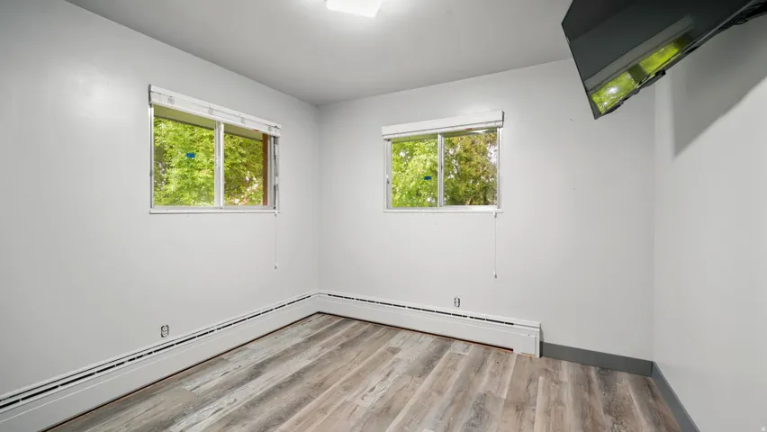 Unfurnished room with light wood-style flooring, healthy amount of natural light, and baseboard heating