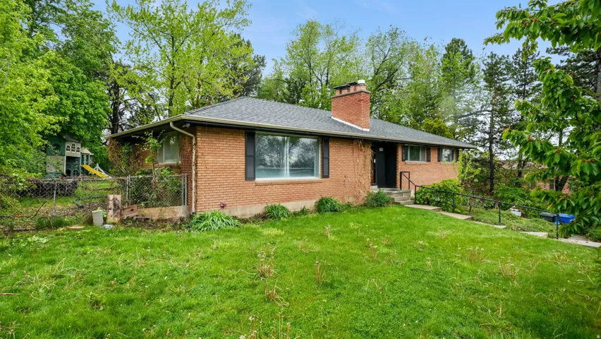Ranch-style home featuring brick siding, a chimney, and roof with shingles