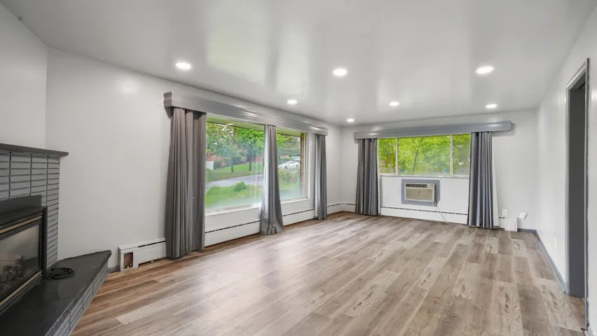 Unfurnished living room featuring a fireplace, light wood-style flooring, baseboard heating, recessed lighting, and healthy amount of natural light