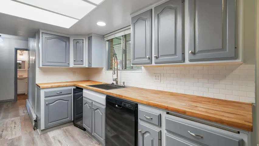 Kitchen featuring gray cabinets, wooden counters, dishwasher, light wood finished floors, and recessed lighting