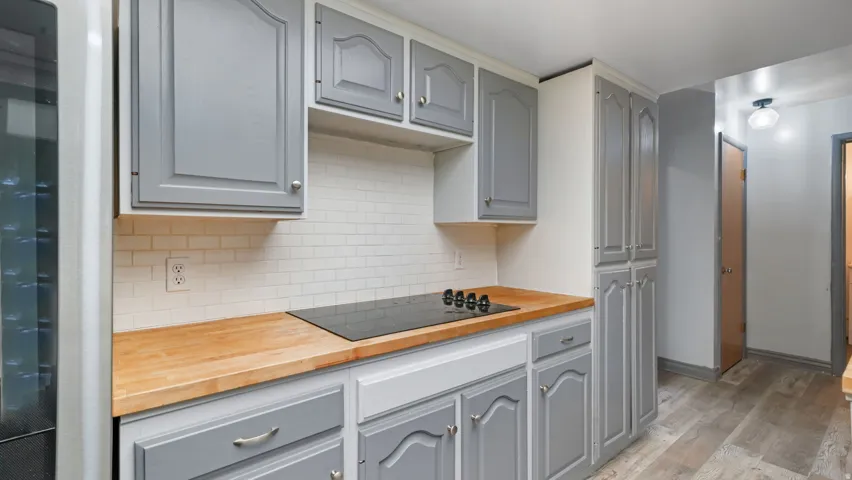 Kitchen with butcher block counters, gray cabinetry, light wood-style floors, and tasteful backsplash