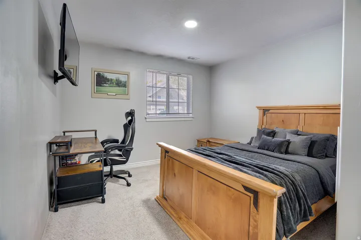 Bedroom with light colored carpet and a desk