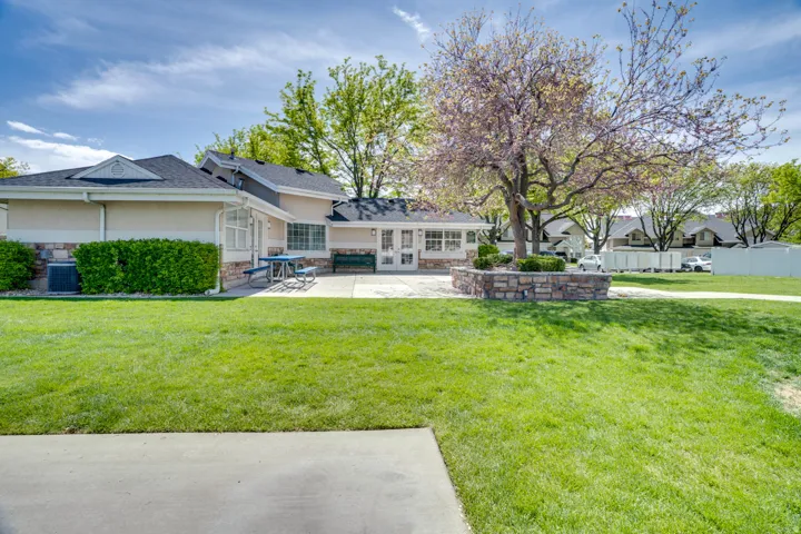 Back of property featuring a patio area, stucco siding, stone siding, and a shingled roof