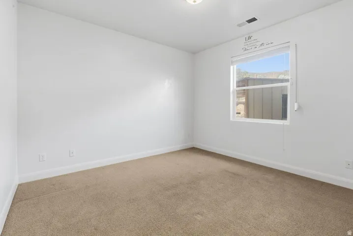 Carpeted spare room featuring baseboards