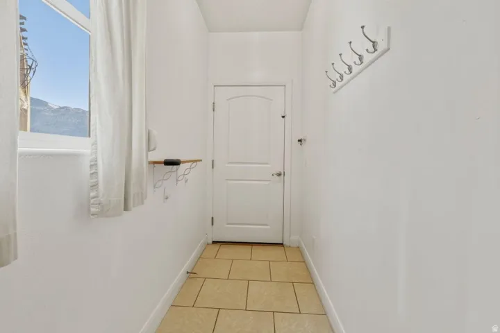 Hall featuring light tile patterned flooring and baseboards