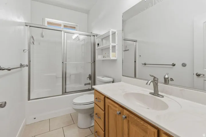 Bathroom with vanity, light tile patterned floors, and enclosed tub / shower combo
