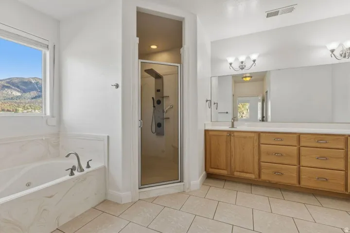 Full bathroom with a shower stall, vanity, a bath, and light tile patterned flooring