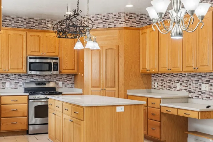 Kitchen with hanging lights, stainless steel appliances, a center island, and tasteful backsplash