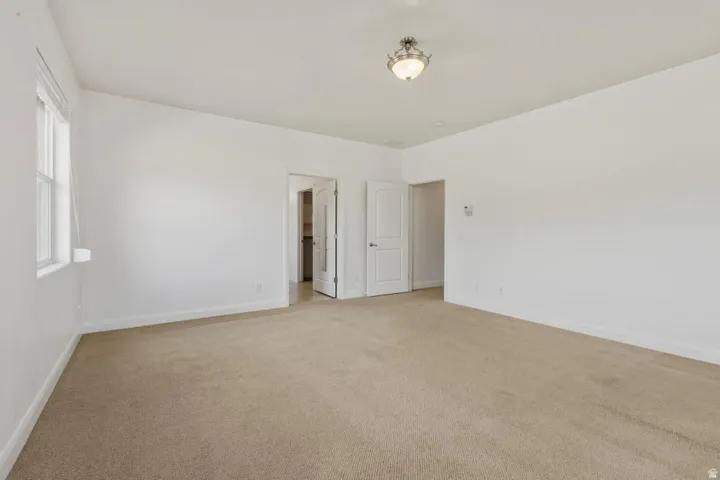Unfurnished bedroom with light colored carpet and baseboards