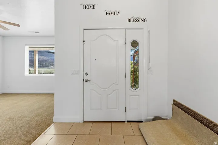 Foyer entrance featuring light carpet, light tile patterned floors, and a ceiling fan