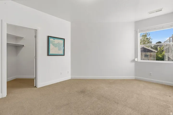 Unfurnished bedroom with a spacious closet and light colored carpet