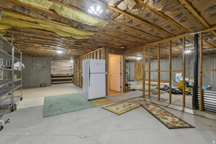 Unfinished basement with freestanding refrigerator