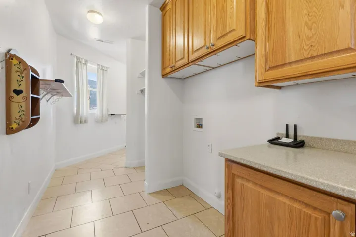 Laundry area with cabinet space, light tile patterned flooring, and washer hookup
